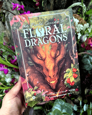 Book titled 'The Field Guide to Floral Dragons' held in front of a floral background