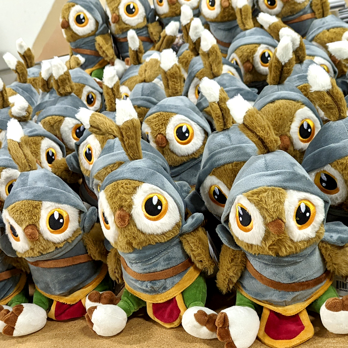 Stack of plush owls dressed in costumes on a wooden surface